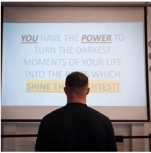 Daniel Wilshire looking at his power point slide with the message, you have the power to turn the darkest moments of your life into shine! 