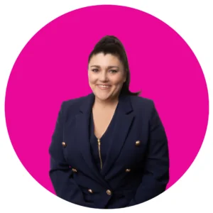 Tracy Heatley headshot wearing navy blue jacket with a pink background for the how to overcome Mental Blocks For Marketing Success