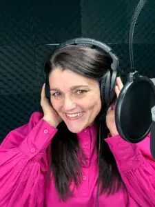 Tracy Heatley, wearing a bright pink shirt and headphones, in her studio recording The Customer Journey Map: Turning Enquiries into Advocates Better Marketing - Bringing You Marketing Magic In Minutes podcast episode
